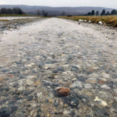 Wasser fließt über einen geschotterten Wirtschaftsweg ab